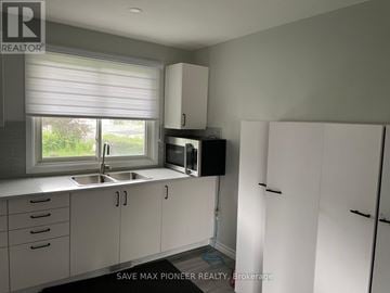 London East (East C) apartment for rent - A kitchen with white cabinets and a window with blinds.
