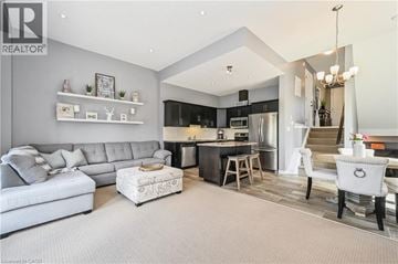 Kitchener apartment for rent - A well-lit, modern living room with a grey sofa and a kitchen area in the background.