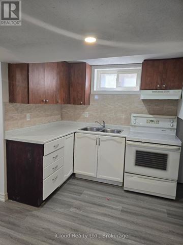 Mississauga (Malton) apartment for rent - A kitchen with white appliances and wooden cabinets.