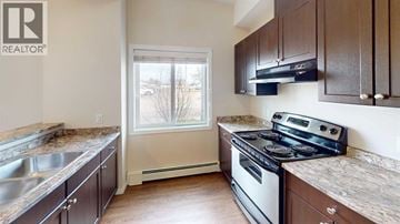 Grande Prairie apartment for rent - A kitchen with brown cabinets and a stove top oven.
