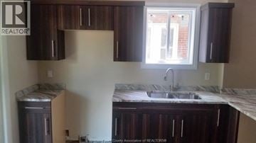 Windsor apartment for rent - A kitchen with dark brown cabinets and a marble countertop.