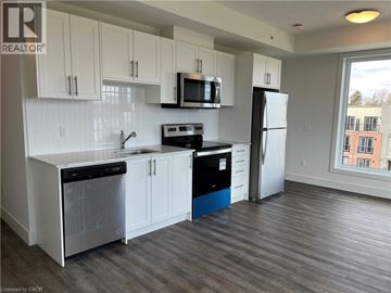 Waterloo condo for rent - A kitchen with white cabinets and a black stove top oven.