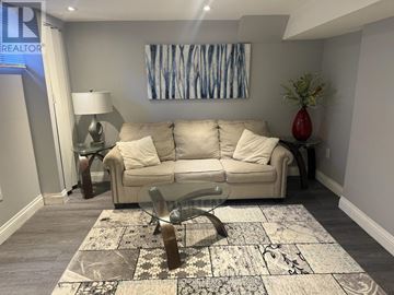 King (Nobleton) apartment for rent - A living room with a white couch, a glass coffee table, and a rug with a black and white pattern.