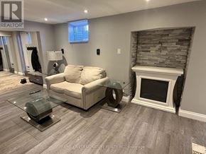 King (Nobleton) apartment for rent - A living room with a beige couch, a glass coffee table, and a stone fireplace.