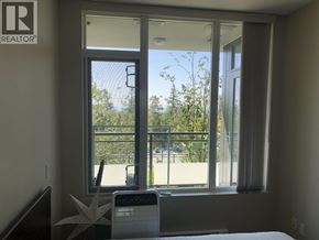 Burnaby apartment for rent - A bedroom with a bed, a window with a view of a fence and trees, and a washing machine.