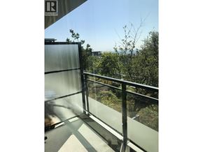 Burnaby apartment for rent - A glass balcony with a metal railing and a view of trees and buildings.