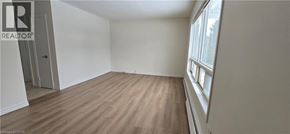 Kitchener apartment for rent - A room with wooden flooring and a window on the right side.