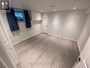 Orillia duplex for rent - A room with a door, a window with blue curtains, and a wooden floor.