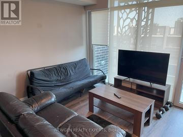 Waterloo condo for rent - A black leather couch sits in a living room with a wooden coffee table in front of it.