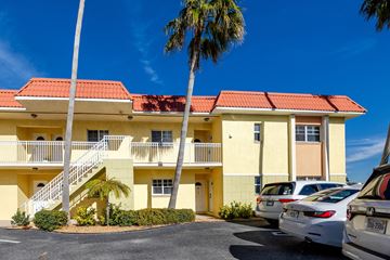 St. Pete Beach apartment for rent - A yellow building with a red roof and a palm tree in front.