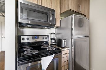 Dallas apartment for rent - A modern kitchen with a stainless steel refrigerator, microwave, oven, and toaster.