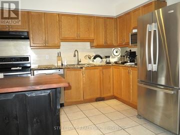 London North (North M) townhouse for rent - A kitchen with wooden cabinets and a stainless steel refrigerator.