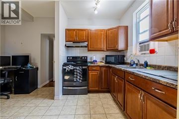 Brantford apartment for rent - A kitchen with brown cabinets and a black stove top oven.