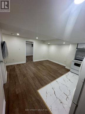 Bradford West Gwillimbury (Bradford) apartment for rent - A spacious room with wooden flooring and a marble patterned area rug.