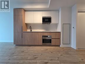 Toronto (Waterfront Communities) condo for rent - A modern kitchen with wooden cabinets and a microwave above the stove.
