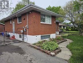 Oshawa (Mclaughlin) apartment for rent - A brick house with a white trim and a small garden in front.