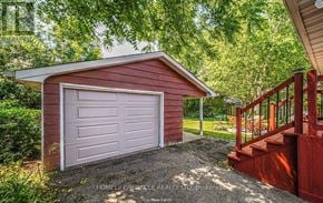 Oshawa (Mclaughlin) apartment for rent - A red garage with a white door is situated in a green area.