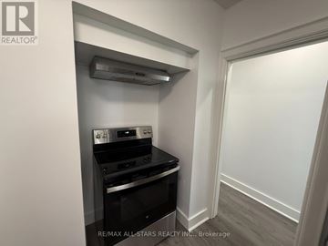Toronto (Long Branch) apartment for rent - A small kitchen with a stove top oven and a wall-mounted range hood.