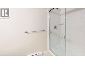Richmond apartment for rent - A white tiled bathroom with a glass shower door.