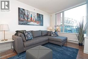 West Vancouver apartment for rent - A living room with a grey couch, a grey ottoman, a lamp, a painting and a plant.
