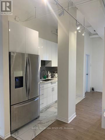 Toronto (Palmerston-Little Italy) condo for rent - A modern kitchen with a stainless steel refrigerator and white cabinets.