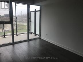 Burlington (Lasalle) condo for rent - A room with a large glass door leading to a view of a parking lot and trees.