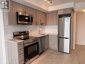Pickering (Bay Ridges) condo for rent - A modern kitchen with stainless steel appliances and wooden cabinets.