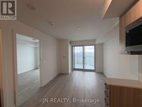Pickering (Bay Ridges) condo for rent - A spacious room with wooden flooring and a sliding glass door leading to a balcony.