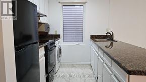 Toronto (Greenwood-Coxwell) duplex for rent - A room with a wooden floor and a window with white curtains.