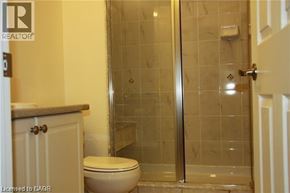 St. Catharines townhouse for rent - A bathroom with a toilet and a glass shower stall.