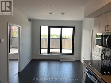 Toronto (Cliffcrest) condo for rent - A kitchen with a stove top oven and a window with a view of a fence and trees.