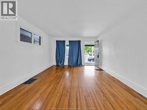 Windsor duplex for rent - A room with wooden flooring and a window with blue curtains.