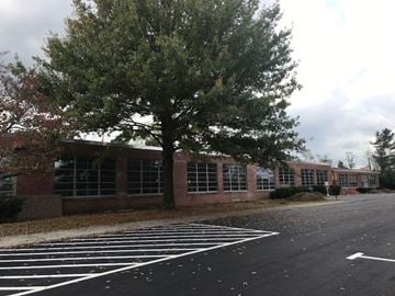 Blacksburg apartment for rent - A parking lot in front of a brick building with a tree.