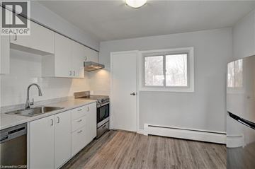 Kitchener condo for rent - A kitchen with white cabinets and a window.
