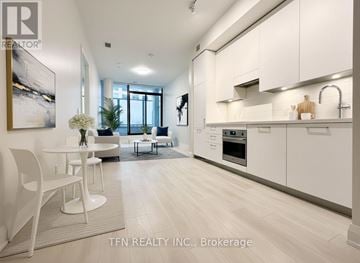 Toronto (Thorncliffe Park) condo for rent - A modern kitchen with white cabinets and a dining table.