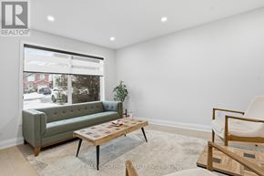 Hamilton (Gilkson) apartment for rent - A living room with a green couch, a wooden coffee table, and a white chair.