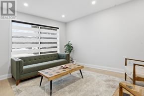 Hamilton (Gilkson) apartment for rent - A living room with a green sofa, a wooden coffee table, and a window with blinds.