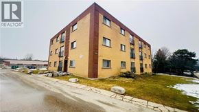 Kitchener condo for rent - A brick building with a green lawn in front.