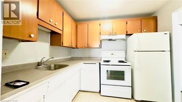 Kitchener condo for rent - A kitchen with white appliances and wooden cabinets.