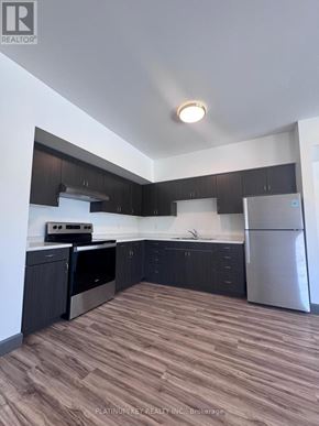 Strathroy-Caradoc (Mount Brydges) townhouse for rent - A kitchen with dark wood cabinets and stainless steel appliances.