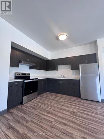 Strathroy-Caradoc (Mount Brydges) townhouse for rent - A kitchen with dark wood cabinets and stainless steel appliances.