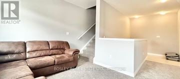 Kitchener townhouse for rent - A living room with a brown leather couch and a white staircase.