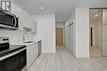 Cambridge condo for rent - A modern kitchen with a black stove top oven and white cabinets.