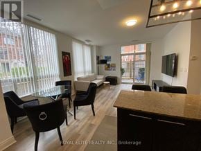 Markham (Commerce Valley) condo for rent - A well-lit living room with a glass table and black chairs.