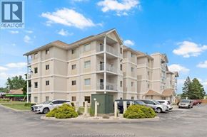 Windsor condo for rent - A large apartment complex with a parking lot in front.