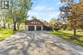 Woodslee apartment for rent - A house with a garage is surrounded by trees.