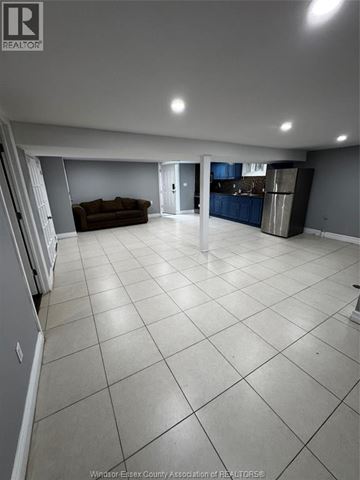 Windsor apartment for rent - A spacious living room with a couch and a kitchen area in the background.