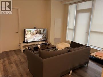Kitchener condo for rent - A living room with a large couch and a television on a stand.