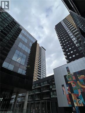Kitchener condo for rent - A tall building with a glass facade stands in front of other buildings.