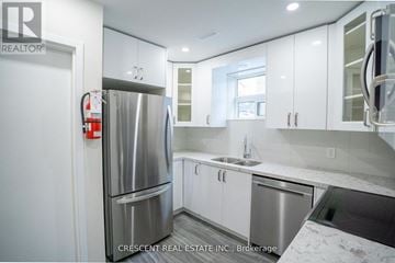 Mississauga (Port Credit) triplex for rent - A kitchen with white cabinets and a stainless steel refrigerator.